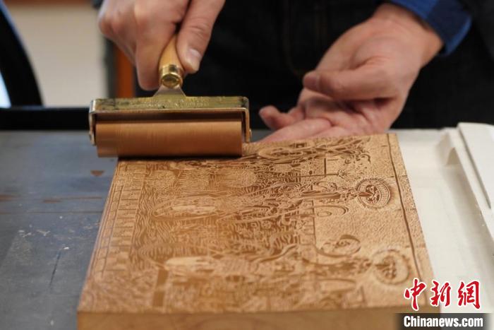 圖為徐晉林工作室工作人員正在給雕好壁畫的版面滾油墨?！【琶赖┰?　攝