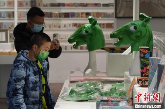 圖為“神馬來(lái)了”銅奔馬頭套吸引參觀者駐足?！【琶赖┰?攝