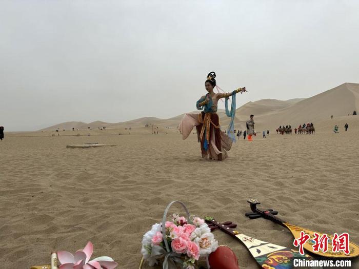 圖為2023年4月底，敦煌大漠“逐舞者”奧楠在鳴沙山月牙泉景區(qū)視頻直播敦煌舞?！●T志軍 攝