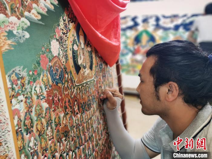 圖為更登才讓的徒弟繪畫(huà)唐卡?！?zhí)砀?攝