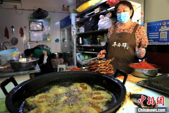 圖為平安驛·河湟民俗文化體驗地內(nèi)的商戶炸干板魚?！⊙Φ?攝